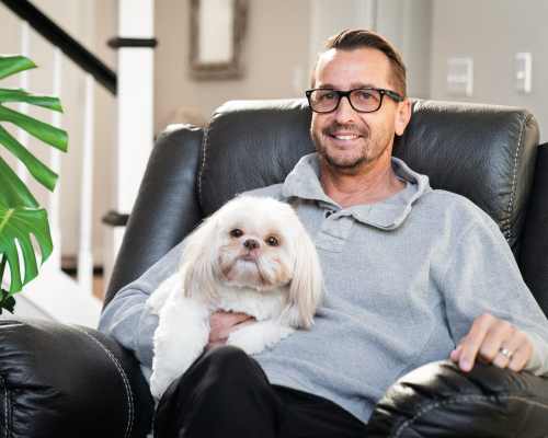 Bill sits in a chair with his dog on his lap